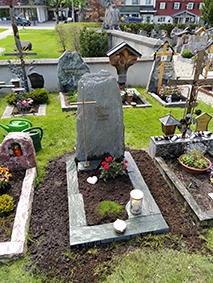 Naturbelassener dunkelgrüner Diabas-Felsstein mit Goldkreuz auf dem Friedhof – STOI Steinmetzwerkstatt