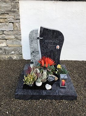 Polierter Blaugranit-Grabstein in geschwungener Form mit Foto-Medaillon und Kreuz-Inlay