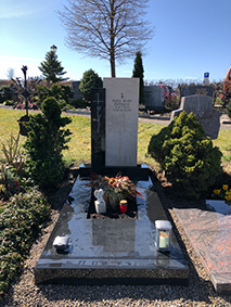 Zweiteiliges Grabmal aus hellem Kalkstein und dunklem Granit mit schlankem Metallkreuz von STOI