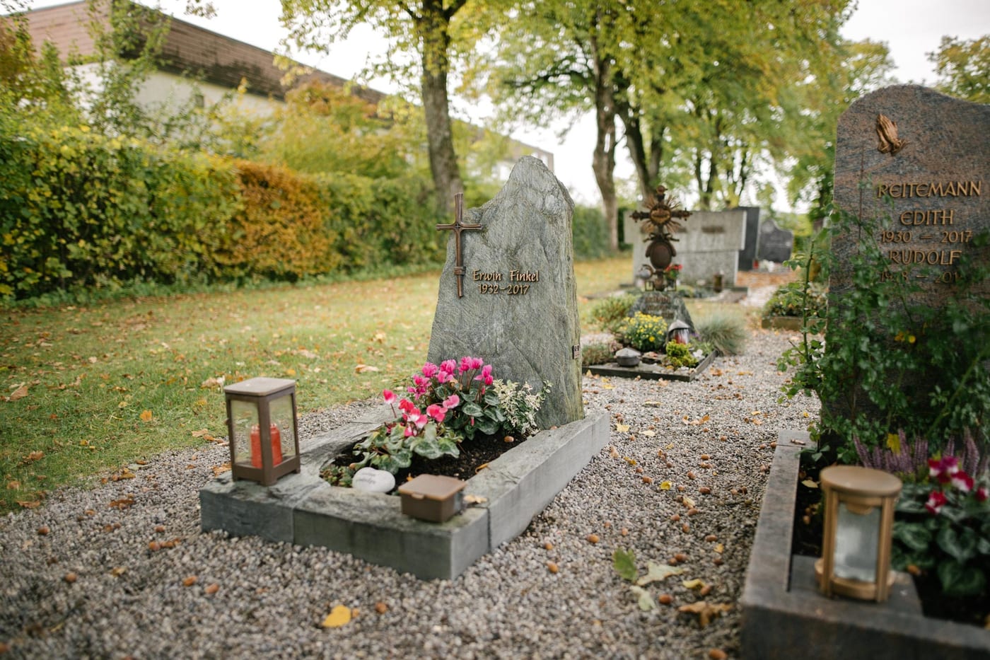 Grüner Serpentinit-Felsgrabstein in massiver organischer Form mit Metallkreuz und passender Grabanlage – Ansicht 3