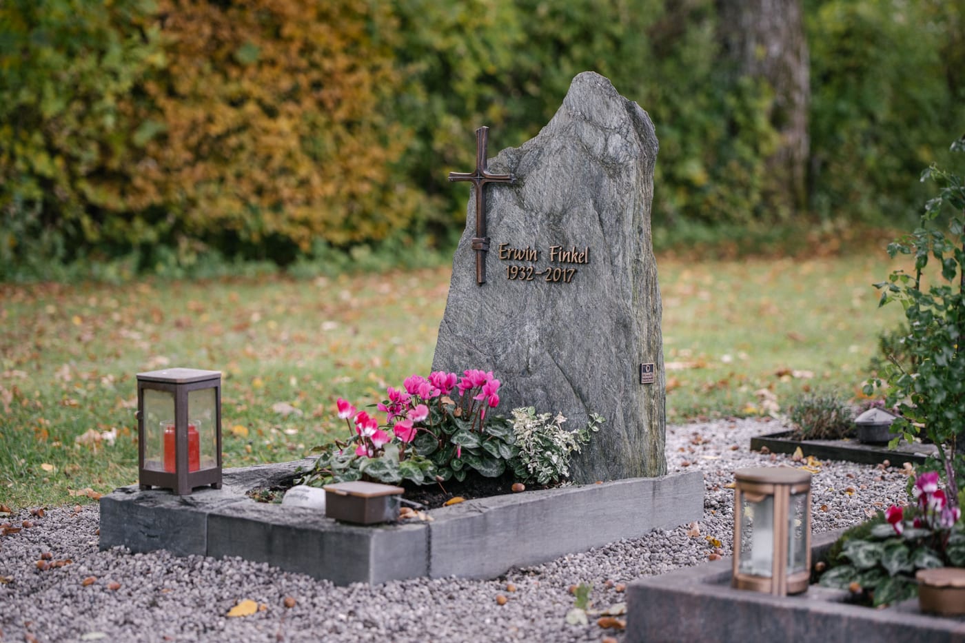 Grüner Serpentinit-Felsgrabstein in massiver organischer Form mit Metallkreuz und passender Grabanlage – Ansicht 4