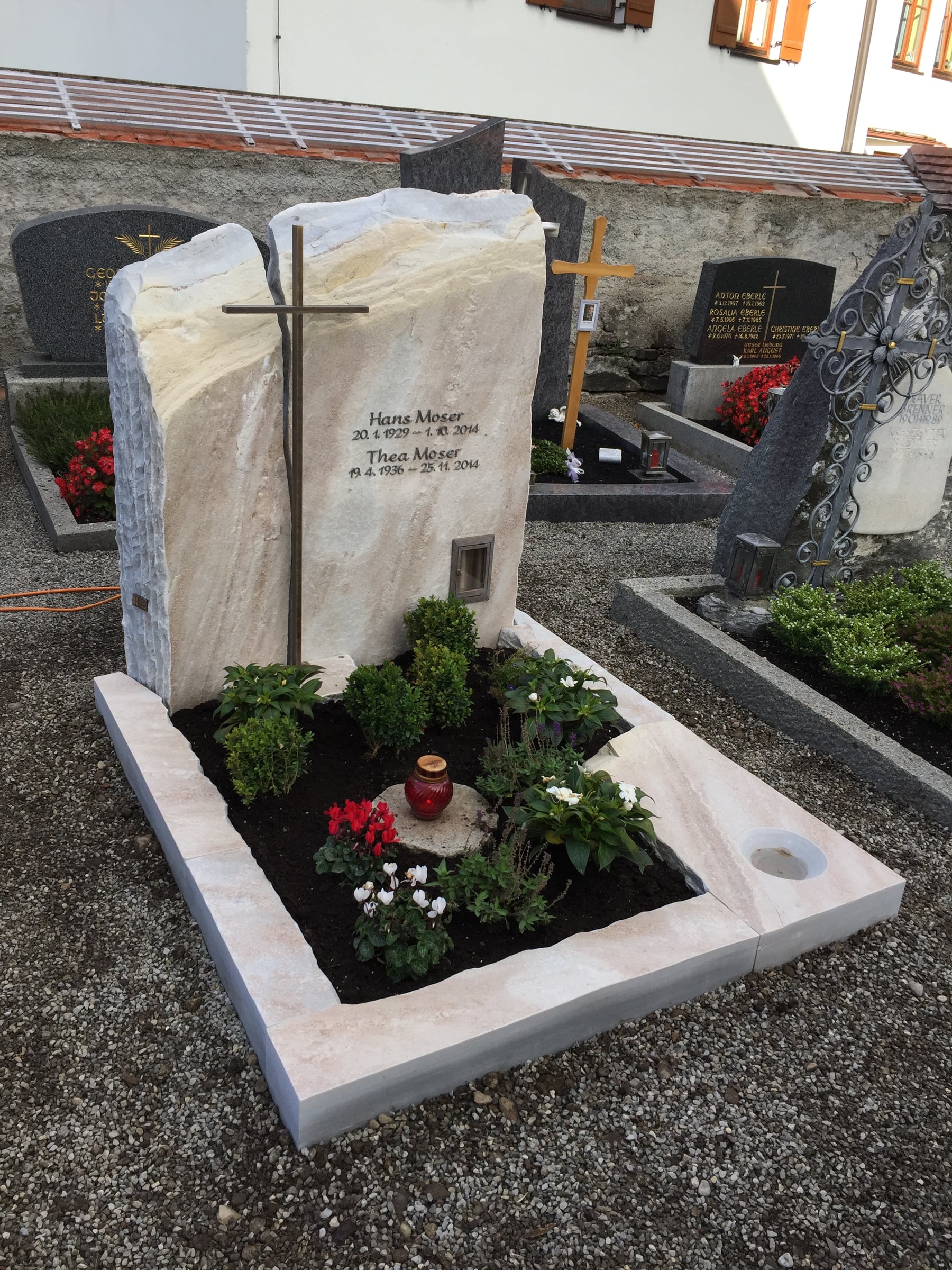 Felsen-Grabstein aus hellem Kalkstein mit naturbelassener Oberfläche und horizontal integriertem Metallkreuz