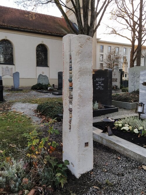 Helle Naturstein-Stele mit integrierten Kieselsteinen und farbigem Akzentelement, STOI Steinmetzwerkstatt