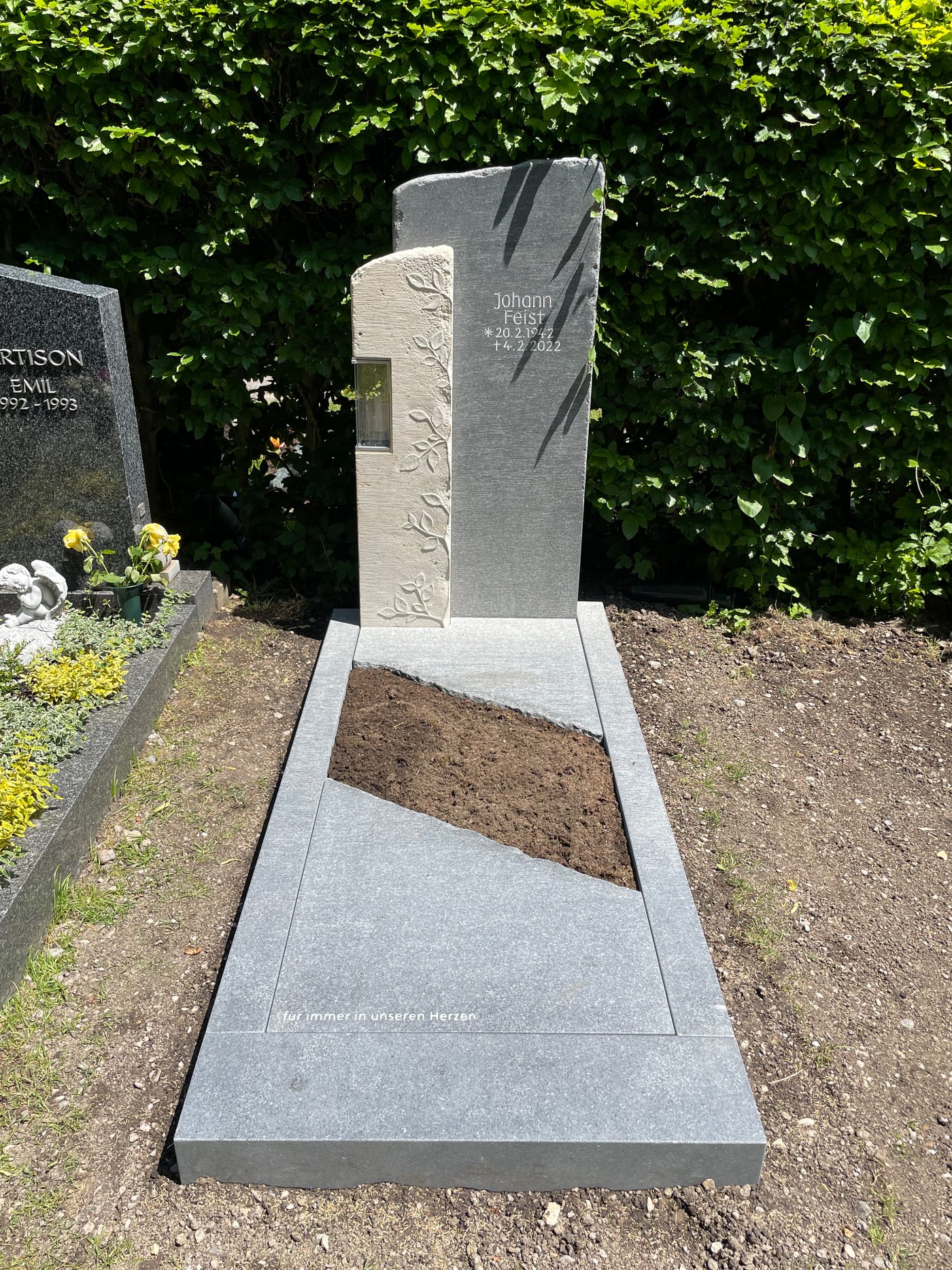 Zweiteiliger dunkelgrauer Granit-Grabstein mit filigranem Ranken-Relief und integrierter Kerze