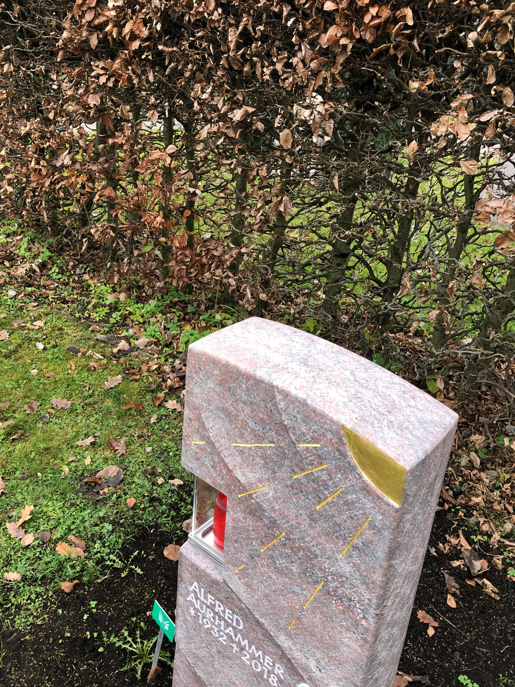 Warmroter Granit-Grabstein mit sandgestrahltem Sonnenmotiv, integrierter Kerze und Porträtmedaillon