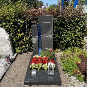 Grauer Granit-Grabstein in Stelenform mit vertikalem leuchtendem Blauglas-Streifen, handwerklich von STOI