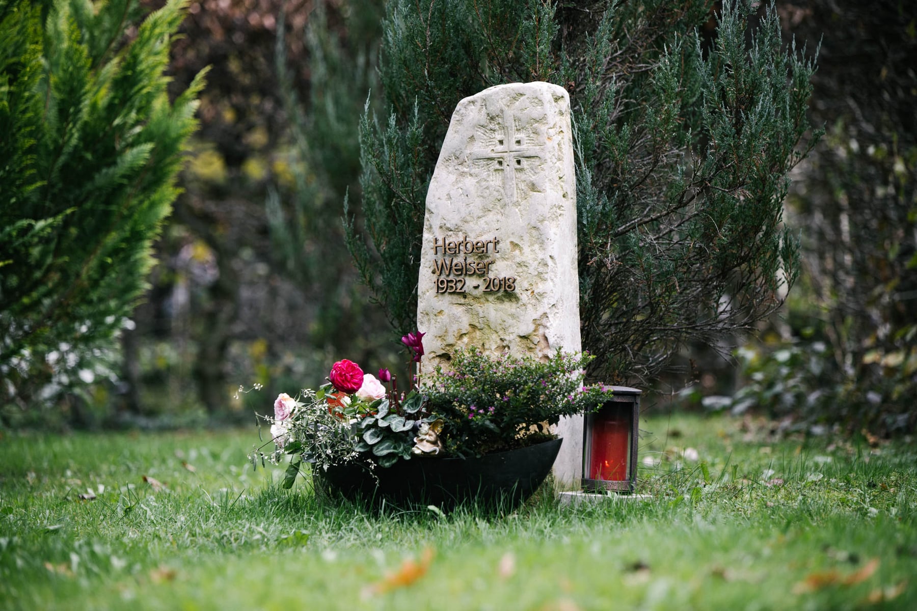Naturbelassener Kalkstein-Findling als Grabstein mit eingravierten Kreuz und goldener Inschrift