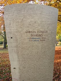 Schlanker Grabstein aus hellem Kalkstein mit sanft geschwungenem Rundbogen-Abschluss und feiner Schriftgravur