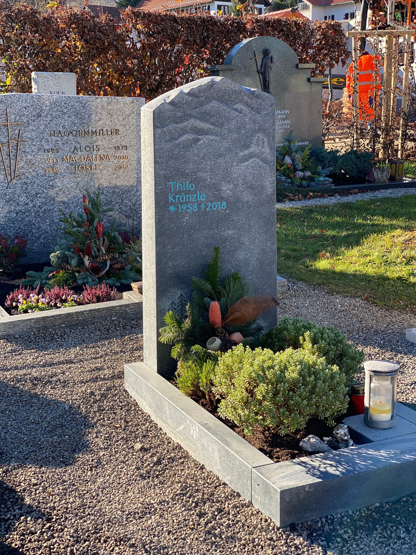 Dunkelgrauer Naturstein-Grabstein mit handwerklich eingearbeitetem Bergpanorama-Relief und organischer Felsform – Ansicht 2