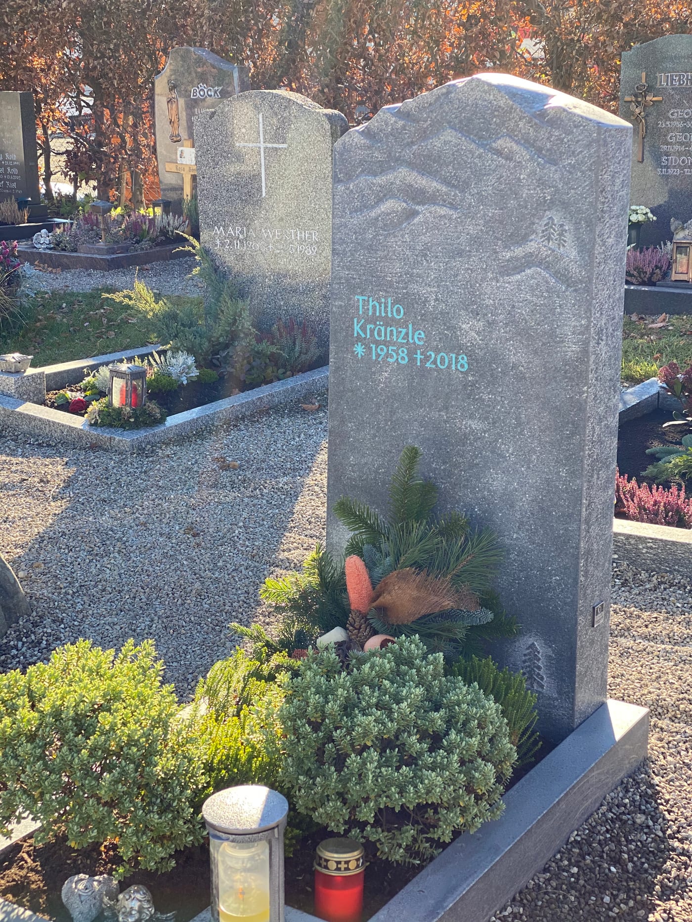 Dunkelgrauer Naturstein-Grabstein mit handwerklich eingearbeitetem Bergpanorama-Relief und organischer Felsform – Ansicht 3