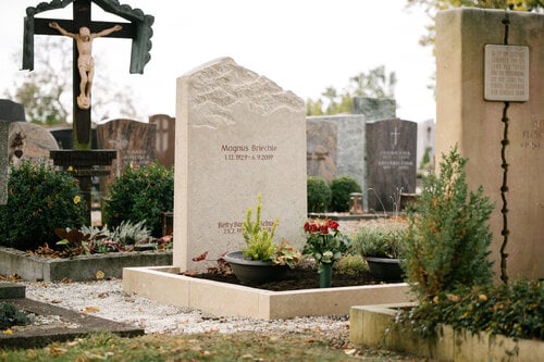 Heller Kalkstein-Grabstein mit sandgestrahltem Bergpanorama-Motiv und geschwungenem Stelenabschluss