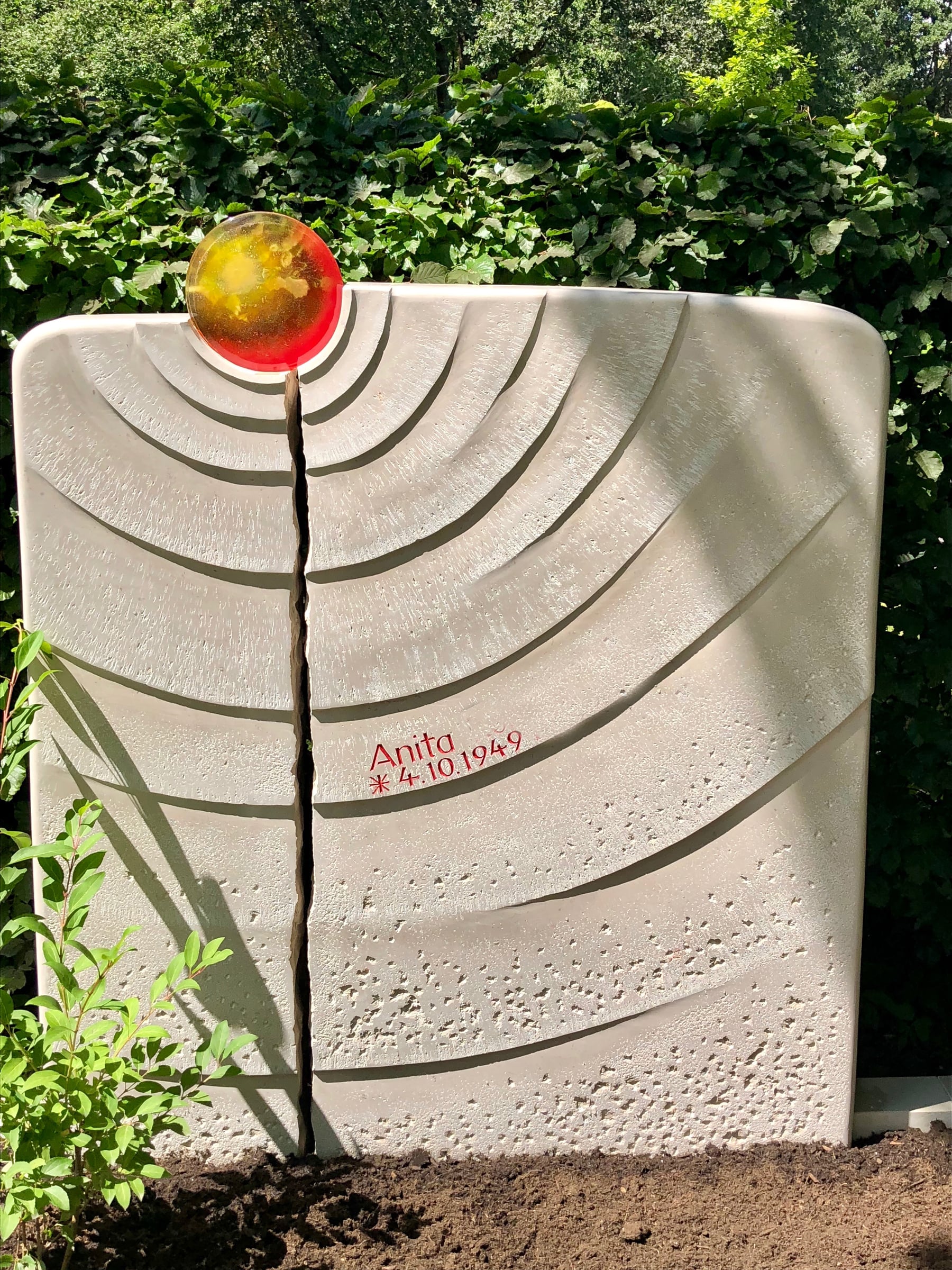 Heller Naturstein-Grabstein mit Stockwerkoberfläche, Kreisrillung und bernsteinfarbener Glaskugel als Sonnen-Motiv