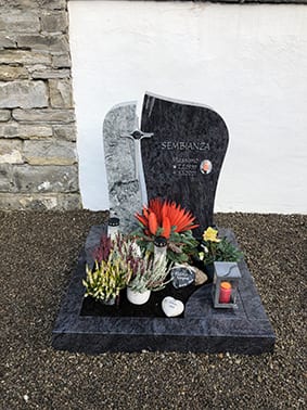 Polierter Blaugranit-Grabstein in geschwungener Form mit Foto-Medaillon und Kreuz-Inlay