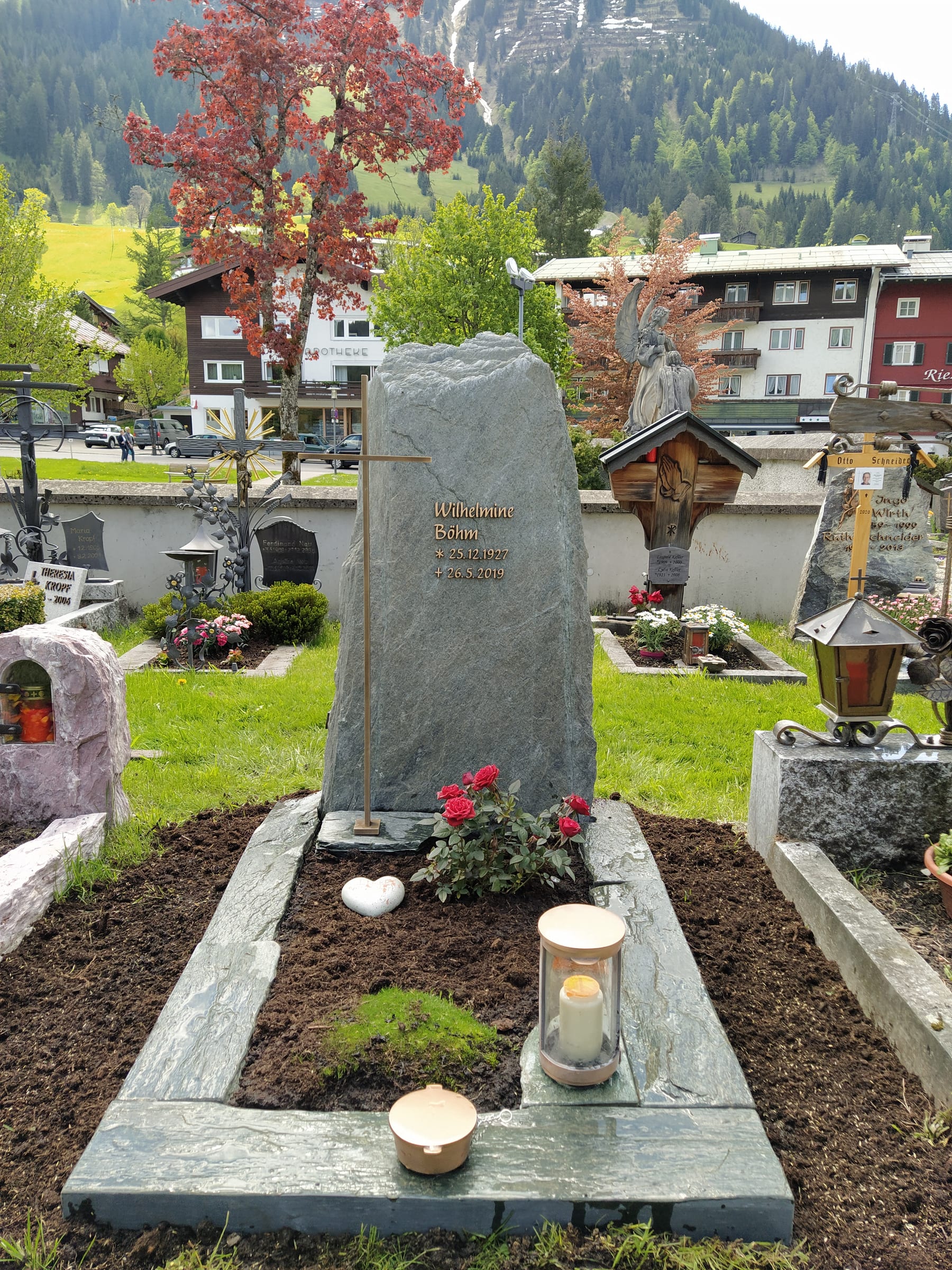 Naturbelassener dunkelgrüner Diabas-Felsstein mit Goldkreuz auf dem Friedhof – STOI Steinmetzwerkstatt