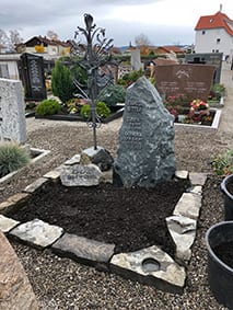 Naturbelassener Felsen-Grabstein mit riesigem ornamentalem Metallkreuz und Bruchstein-Einfassung von STOI