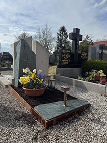 Grabstein aus dunkelgrünem Gneis mit Kreuz und Felsblock in Corten-Stahl-Rosteinfassung