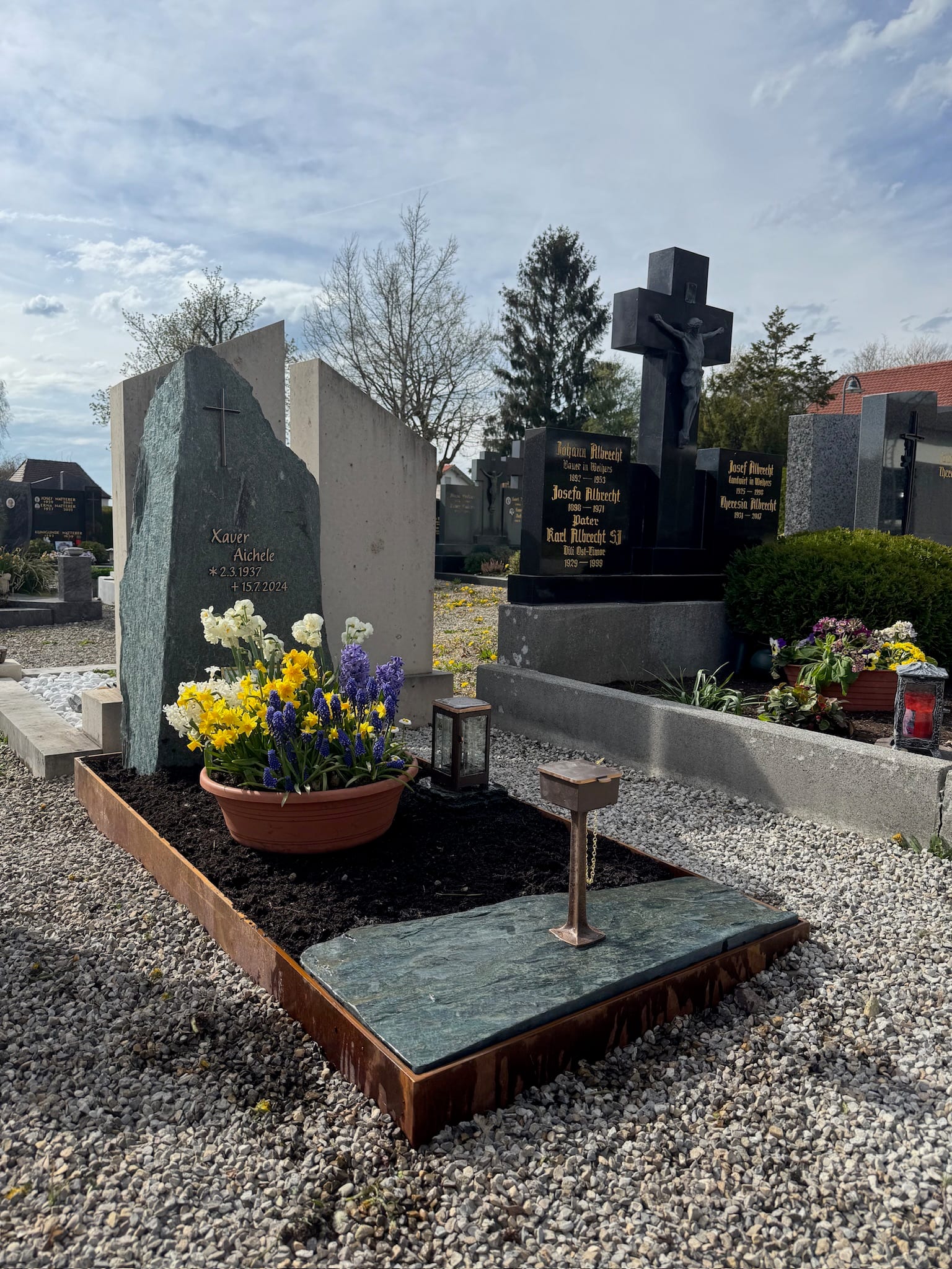 Grabstein aus dunkelgrünem Gneis mit Kreuz und Felsblock in Corten-Stahl-Rosteinfassung