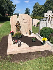 Zweiteiliger Grabstein aus rosafarbenem Kalkstein mit Rundbogen-Form und Bronzemadonna in der Mitte