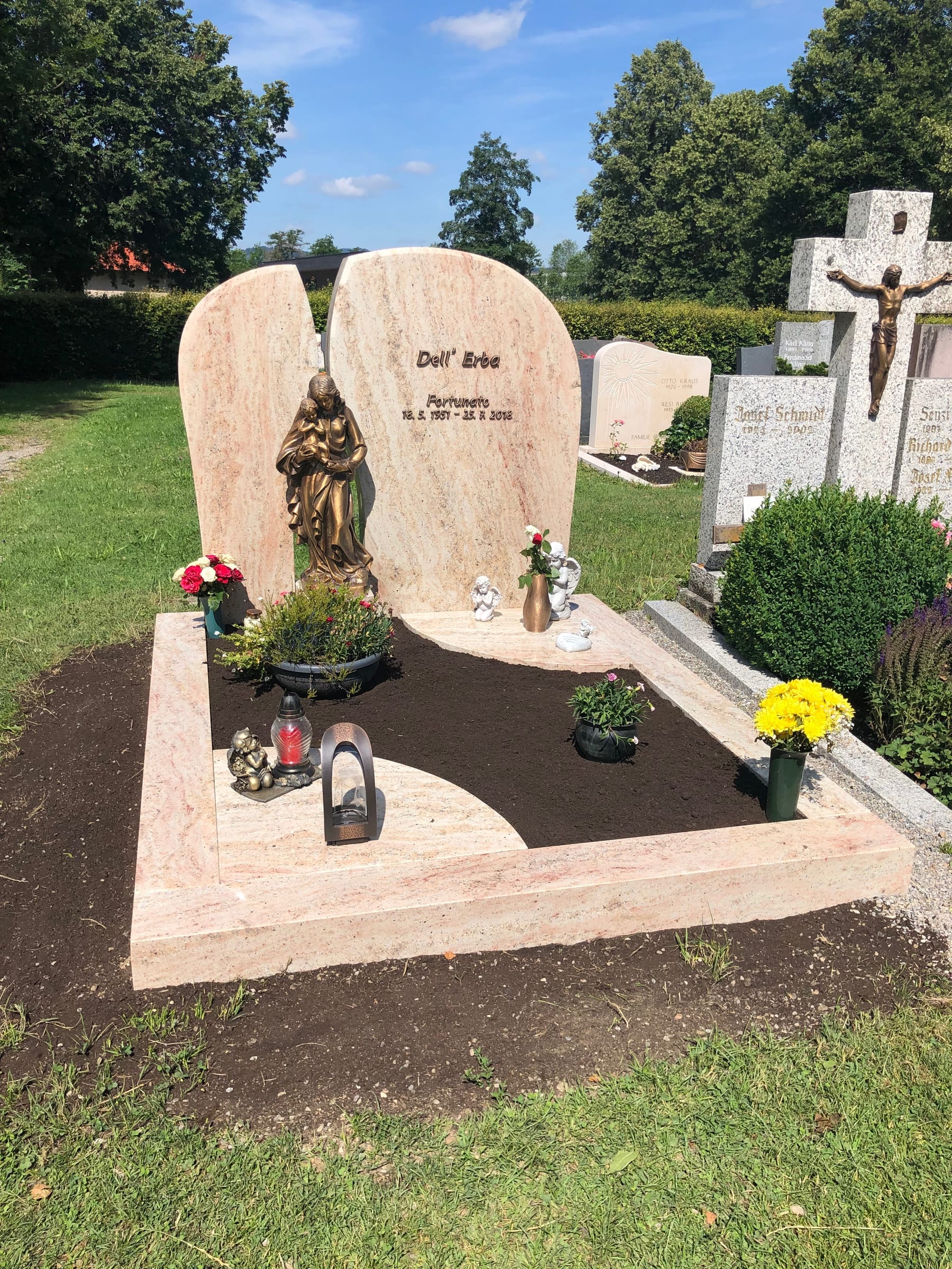 Zweiteiliger Grabstein aus rosafarbenem Kalkstein mit Rundbogen-Form und Bronzemadonna in der Mitte