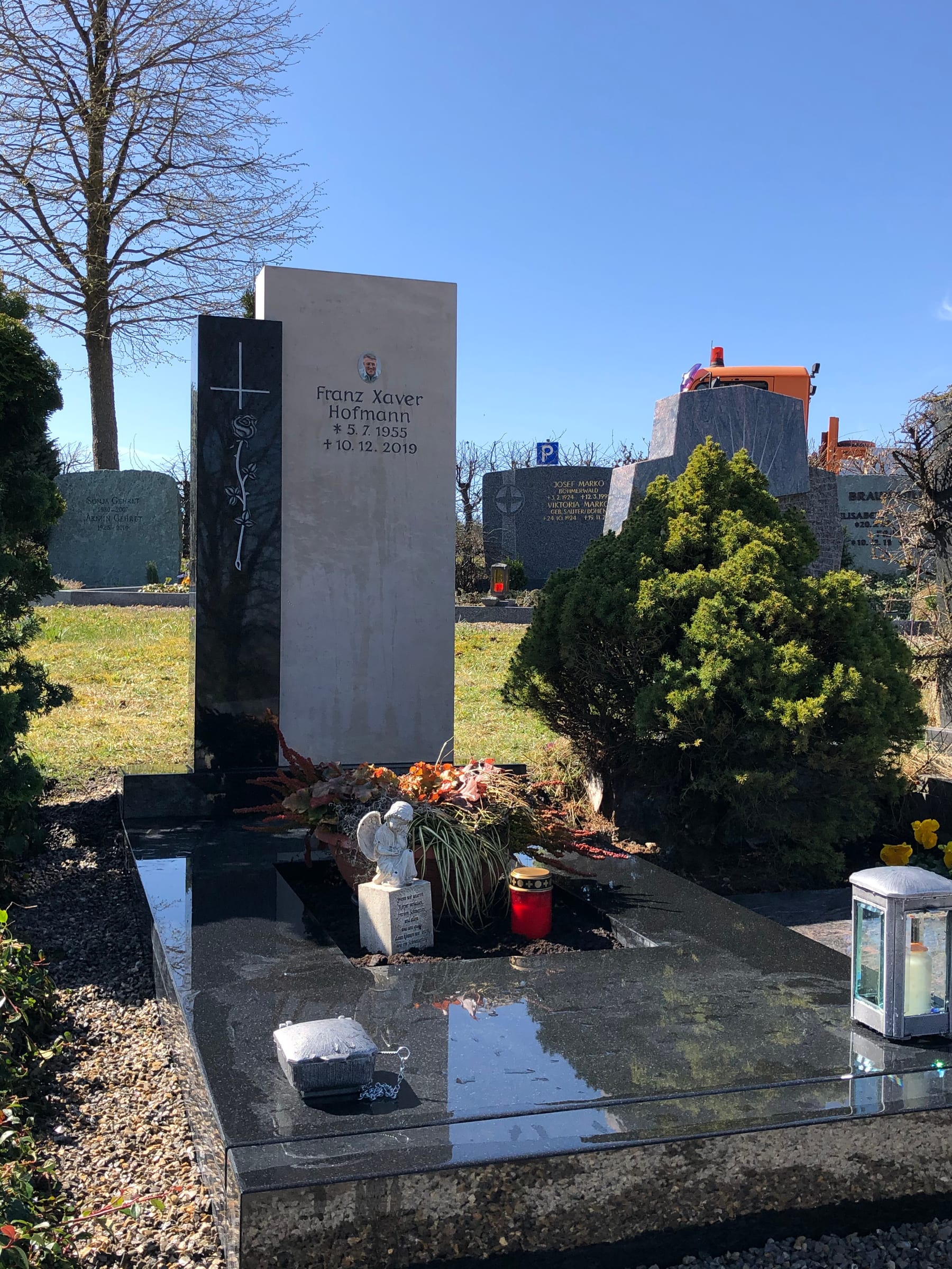 Zweiteiliges Grabmal aus hellem Kalkstein und dunklem Granit mit schlankem Metallkreuz von STOI