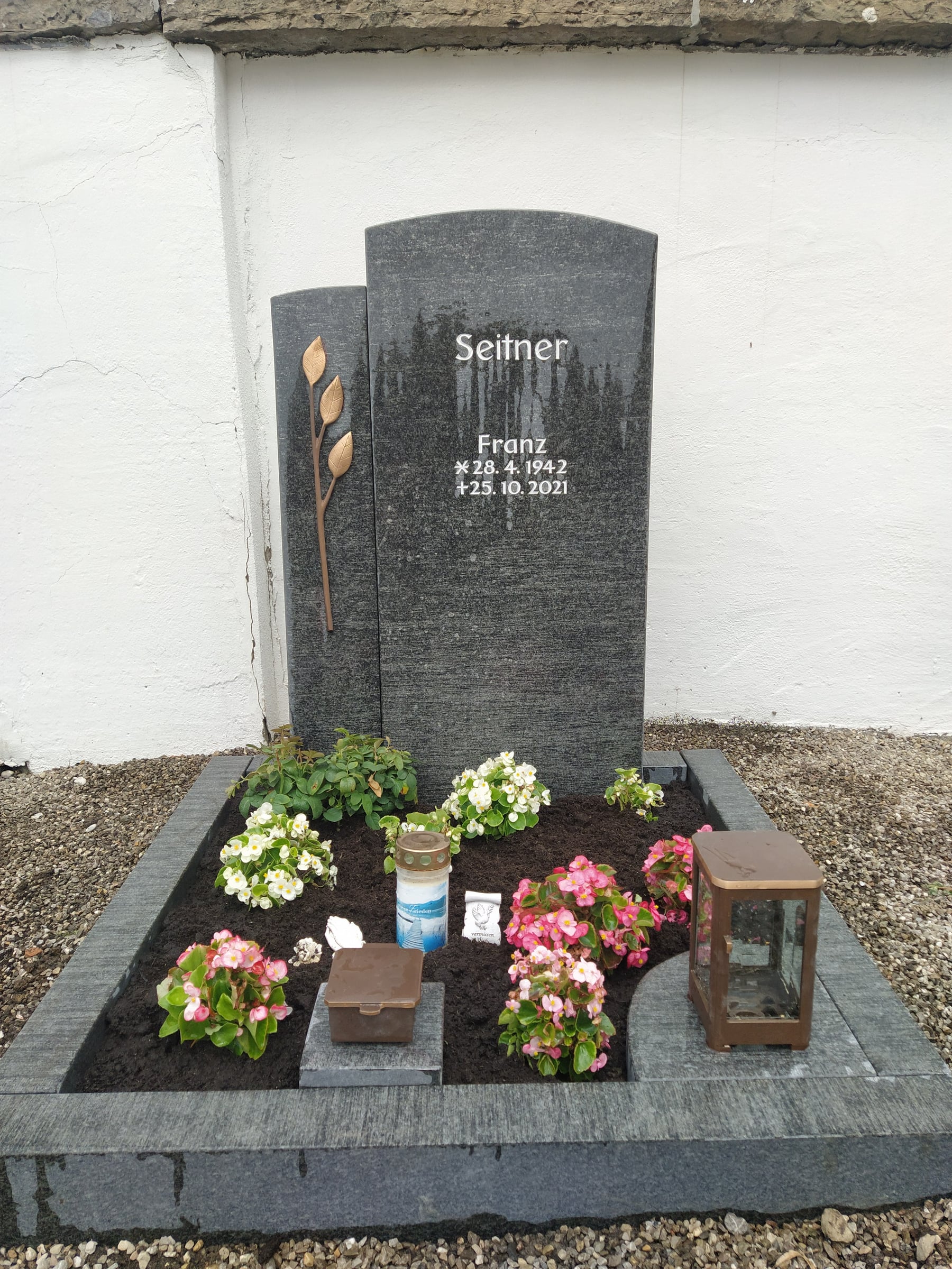 Dunkelgrauer polierter Grabstein mit geschwungener Kontur und Bronzeblatt-Pflanzenmotiv