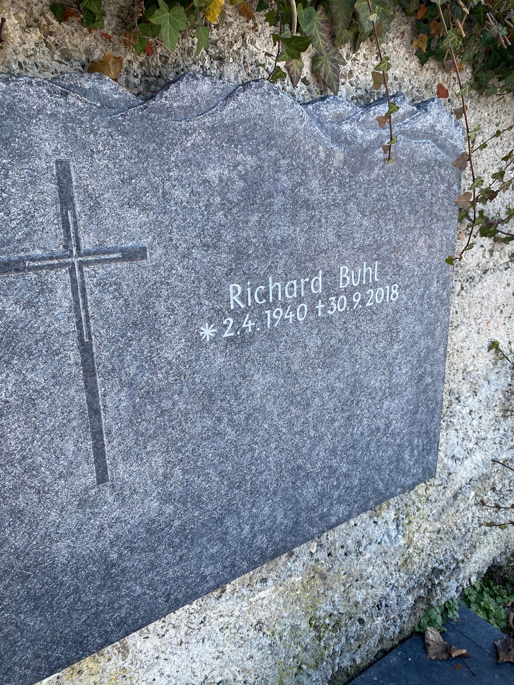 Anthrazit-Granit Wandgrabstein mit unregelmäßiger Bruchkante und passendem dunklen Liegestein