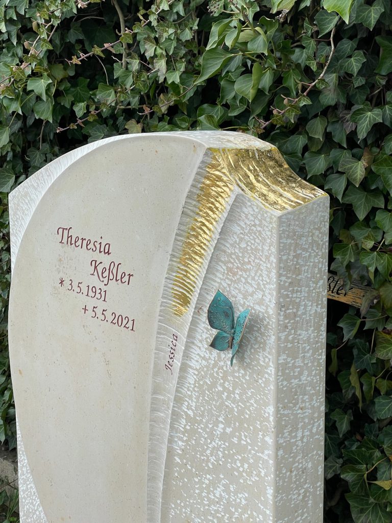 Heller Kalkstein-Grabstein mit geschwungenem Steinschnitt und farbig vergoldetem Schmetterlings-Motiv in Gold und Türkis – Ansicht 4