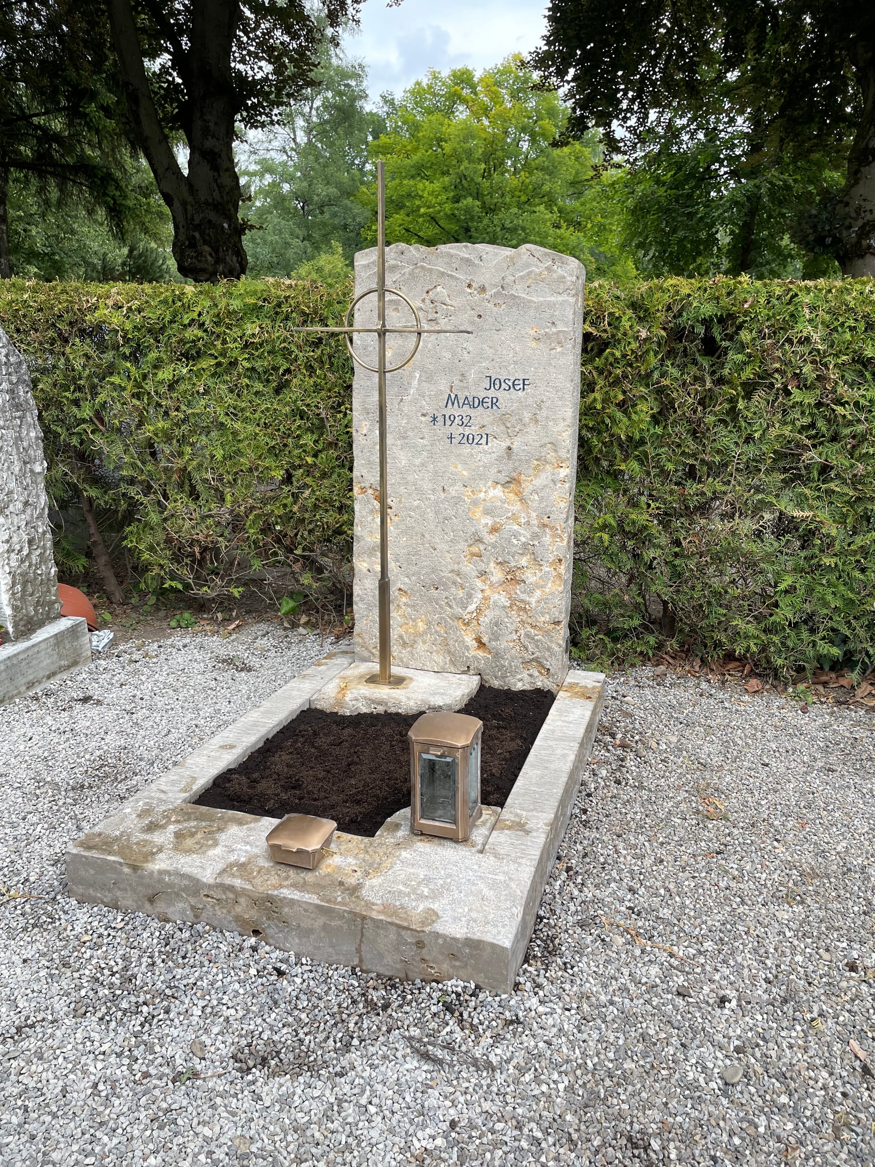 Grabstein aus Jura-Kalkstein mit Bergpanorama-Silhouette und goldenem Metallkreuz von STOI Steinmetzwerkstatt