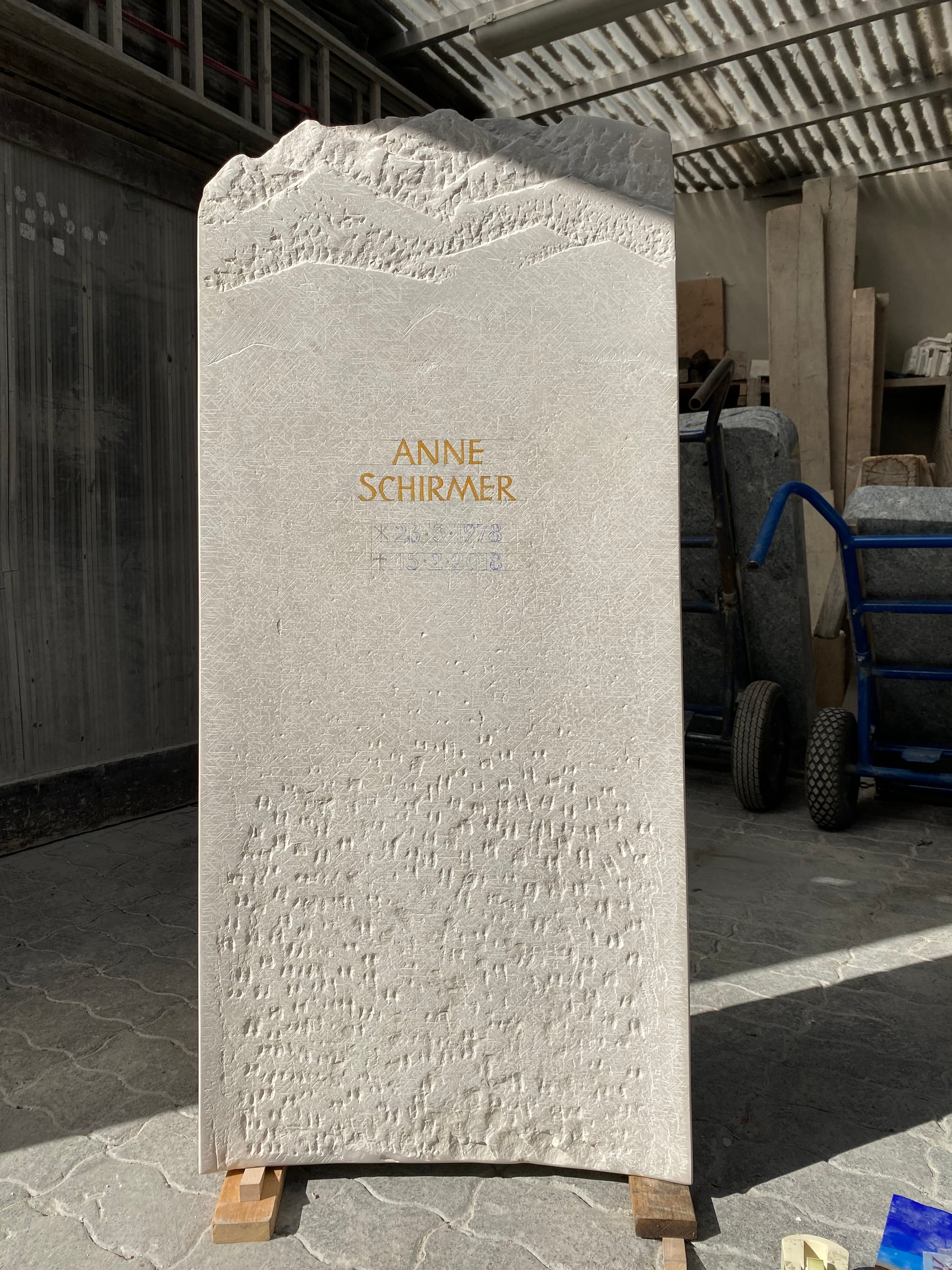Helle schlanke Kalkstein-Stele mit Bergsilhouette als geschwungenem Abschluss von STOI Steinmetzwerkstatt
