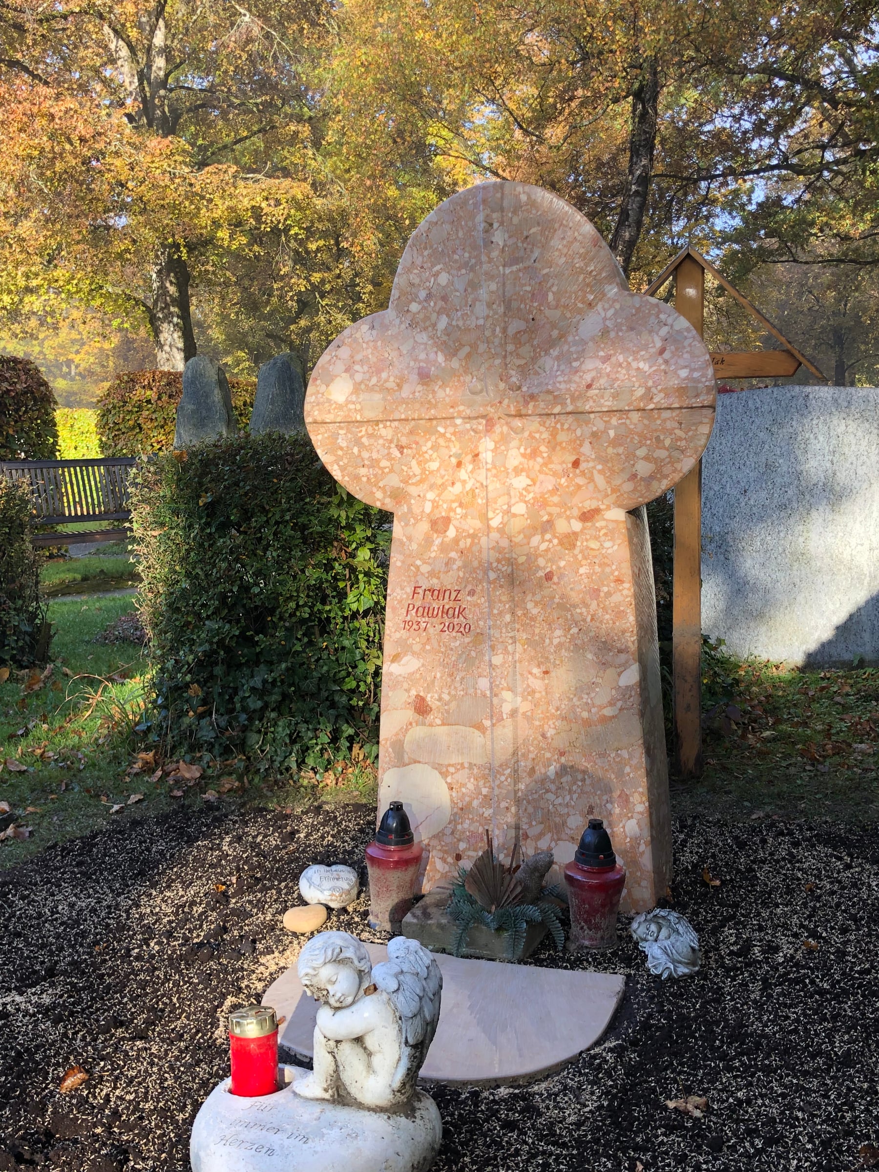 Rosa Naturstein-Grabstein mit charakteristischer dreiteiliger Kleeblatt-Kopfform und eingravierten Blumen