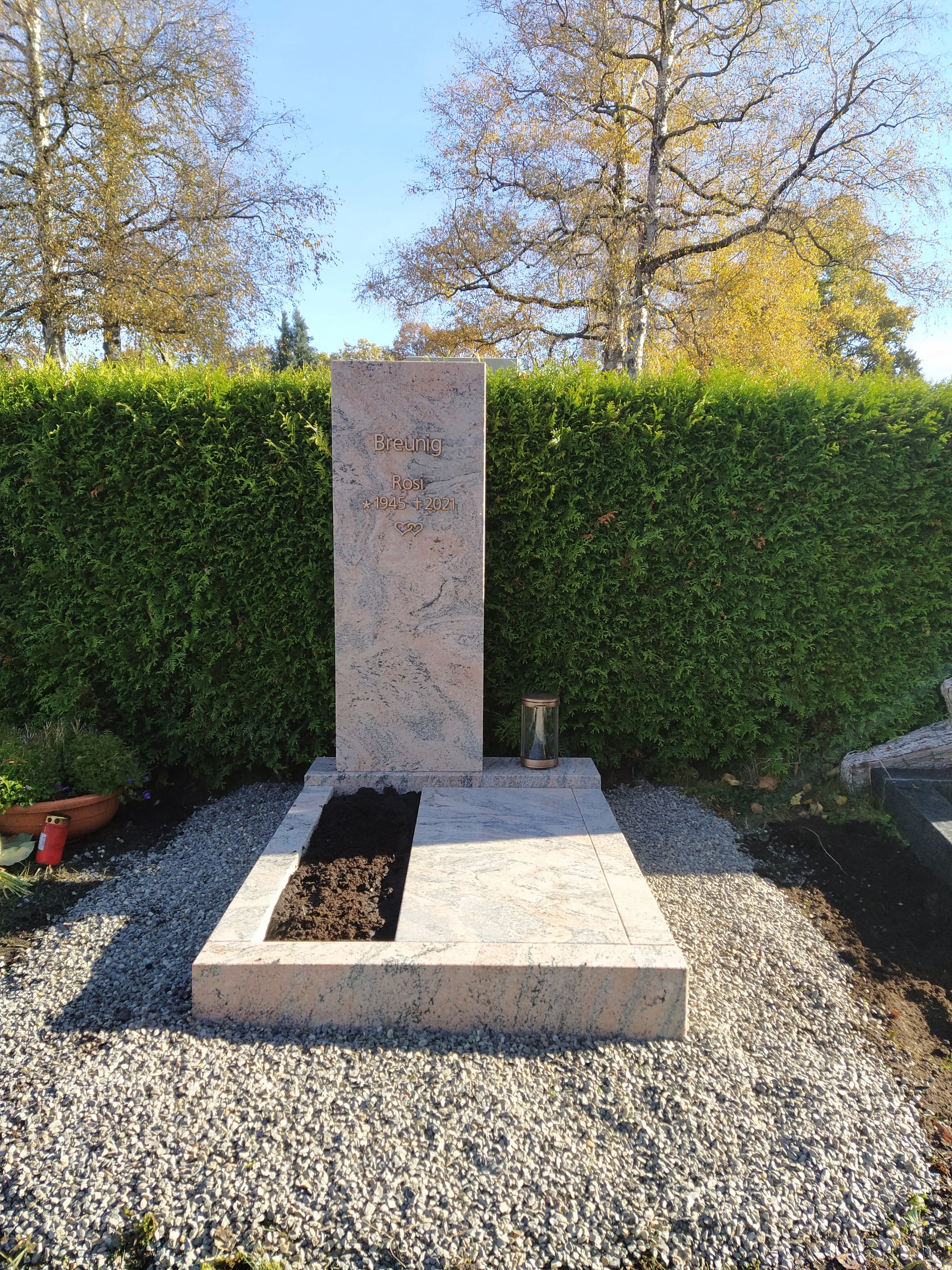 Handwerklicher Kreuzgrabstein aus hellem Kalkstein mit floralen Reliefmotiven und organischer Steinstruktur