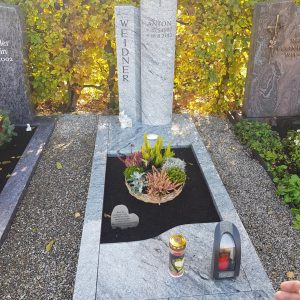 Zweiteilige Stele aus hellem Granit mit eingraviertem Kreuz und dunklem poliertem Liegestein