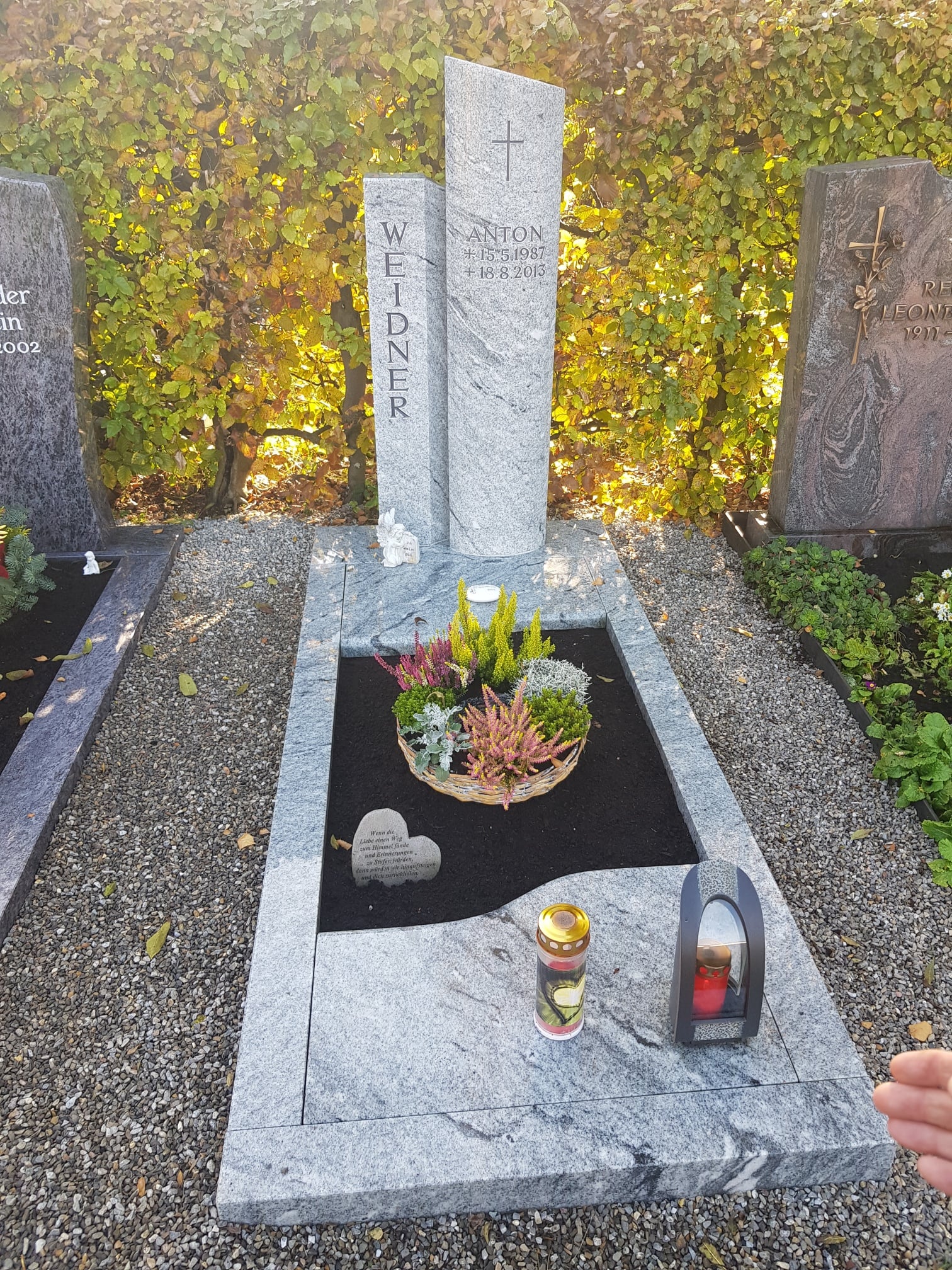 Zweiteilige Stele aus hellem Granit mit eingraviertem Kreuz und dunklem poliertem Liegestein