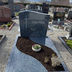 Blaugrauer polierter Granit-Grabstein mit geschwungener Wellenoberkante und eingraviertem Kreuz