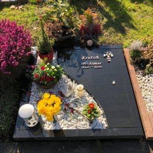 Polierter dunkelgrauer Granit-Liegestein für Urnengrab mit geschwungenem Bogendurchbruch und Schriftgravur