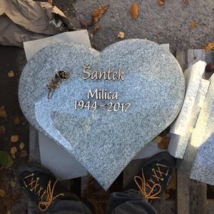 Herzförmiger Liegestein aus hellgrauem Granit mit polierter Oberfläche und Bronzerose-Schmuckelement