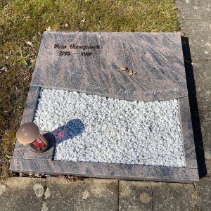 Liegestein aus Rosa-Multicolor-Granit für Urnengrab mit eingelassenem weißen Kiesfeld und dekorativem Element