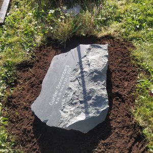 Liegender Felsen-Grabstein aus dunklem Gneis mit organischer Naturform für Urnengrab von STOI