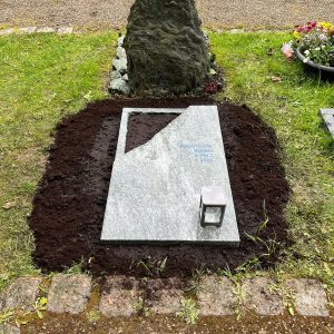 Flacher Granit-Liegestein mit diagonaler Bruchkante, polierter und rauer Oberfläche, mit Fels-Hintergrundstein