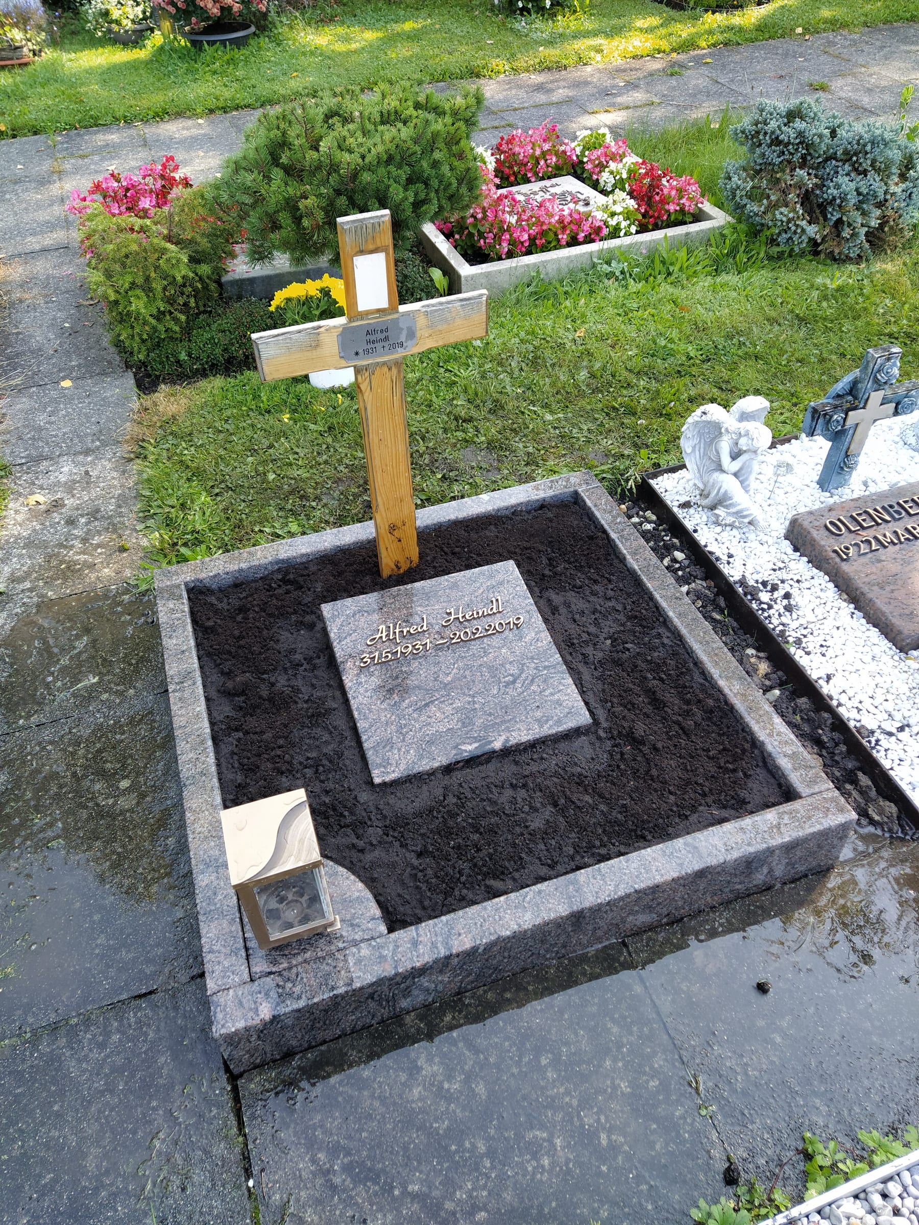 Flacher Urnenliegestein aus anthrazitfarbenem Granit mit polierter Inschriftfläche und Granitrahmeneinfassung