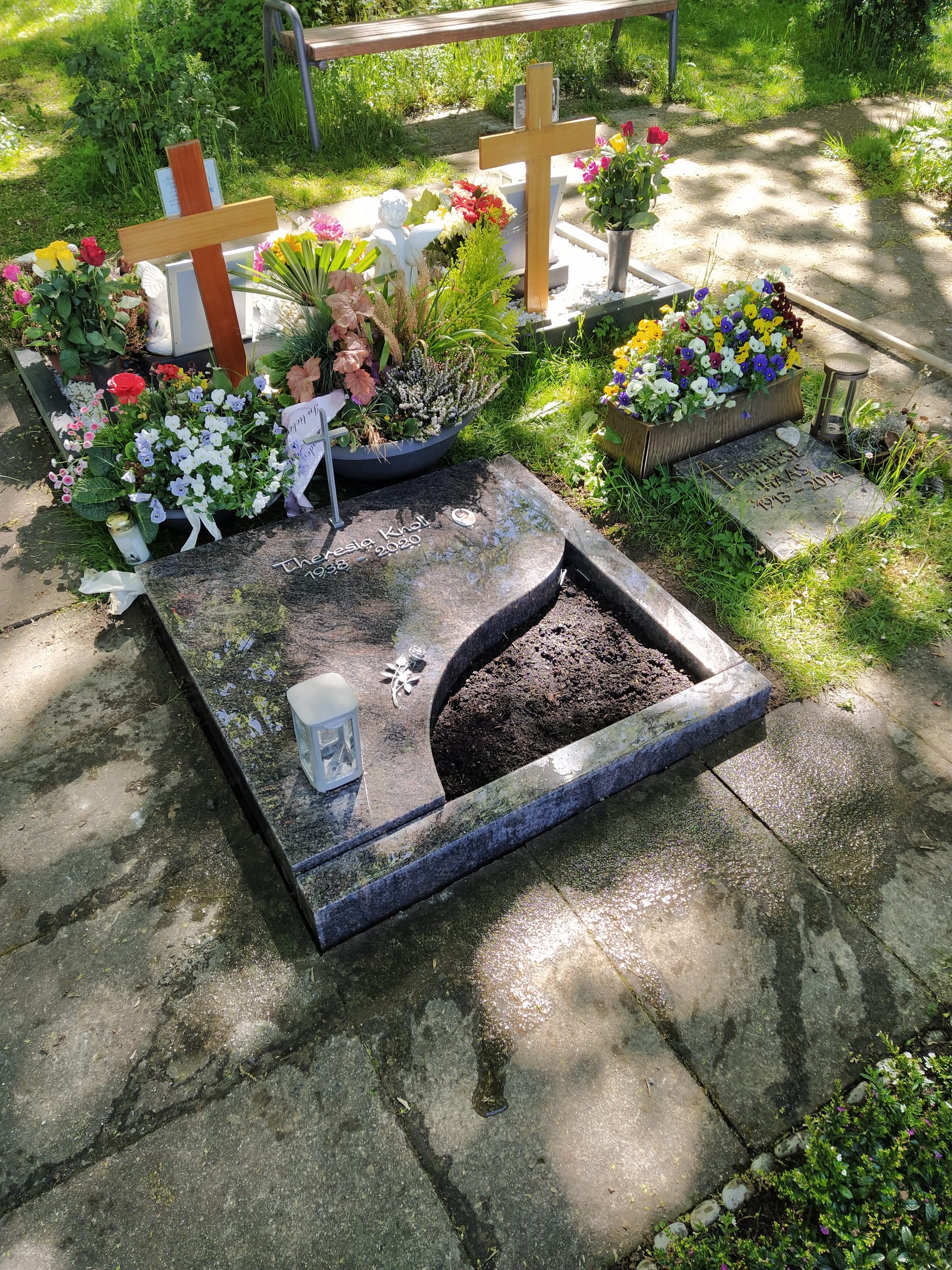 Urnenliegestein aus blaugrauem Naturstein mit geschwungener Wellenform und offener Pflanzfläche